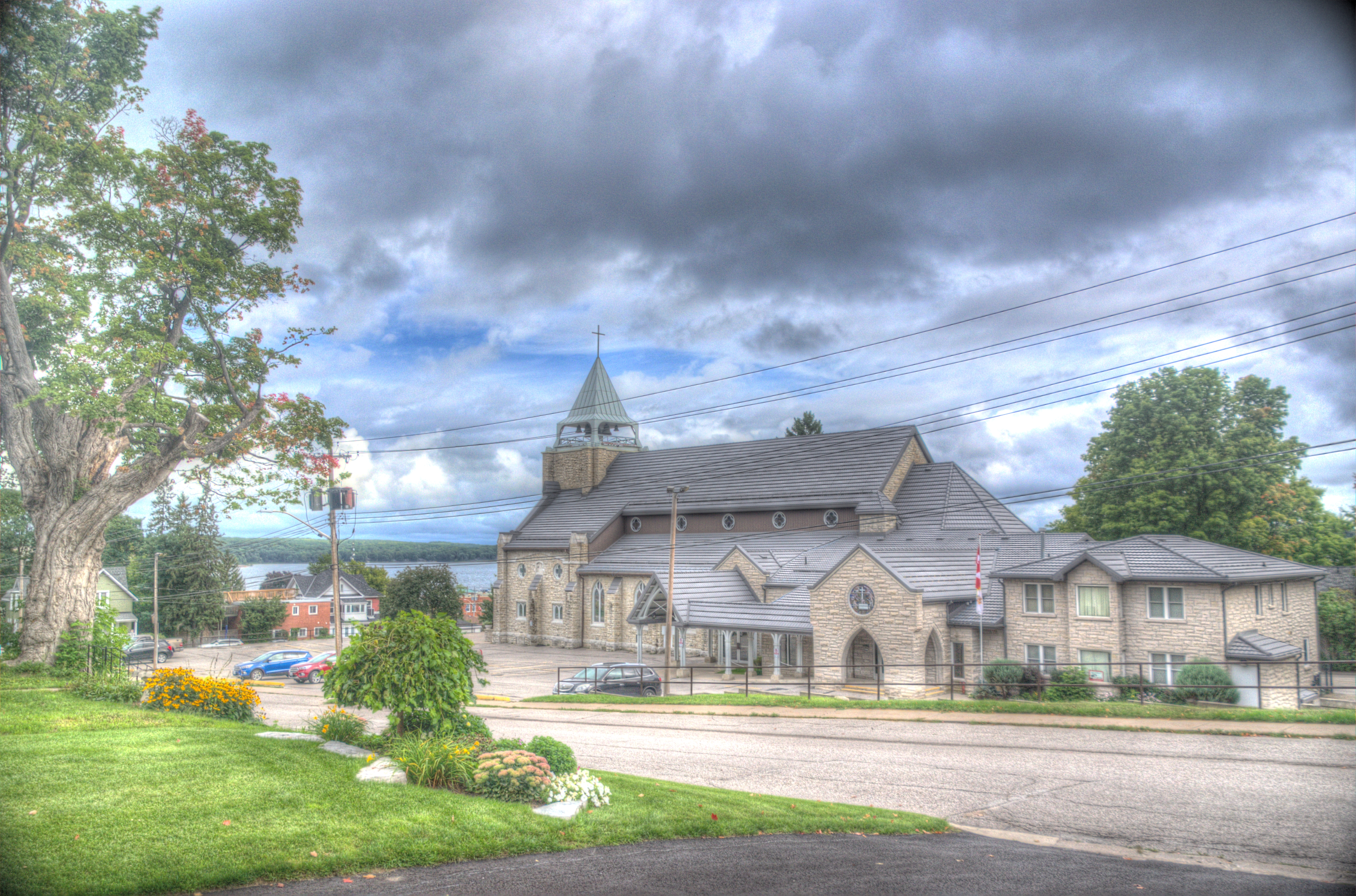 Outside image of St. Margaret's from the view of Third St. with a tree on the left and beautiful clouds.