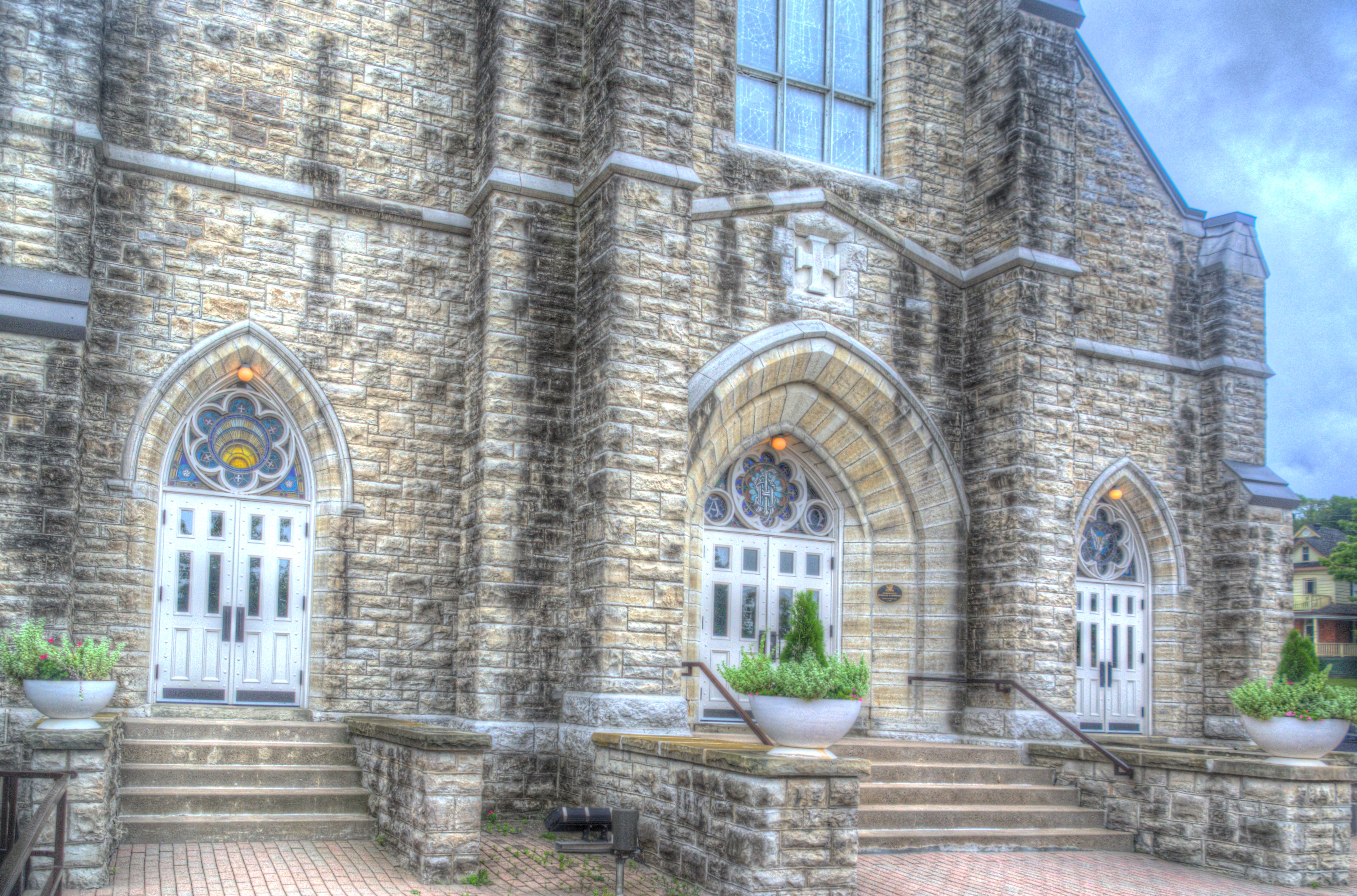 Outside image of St. Margaret's beautiful front doors with a stain glass above the doors.