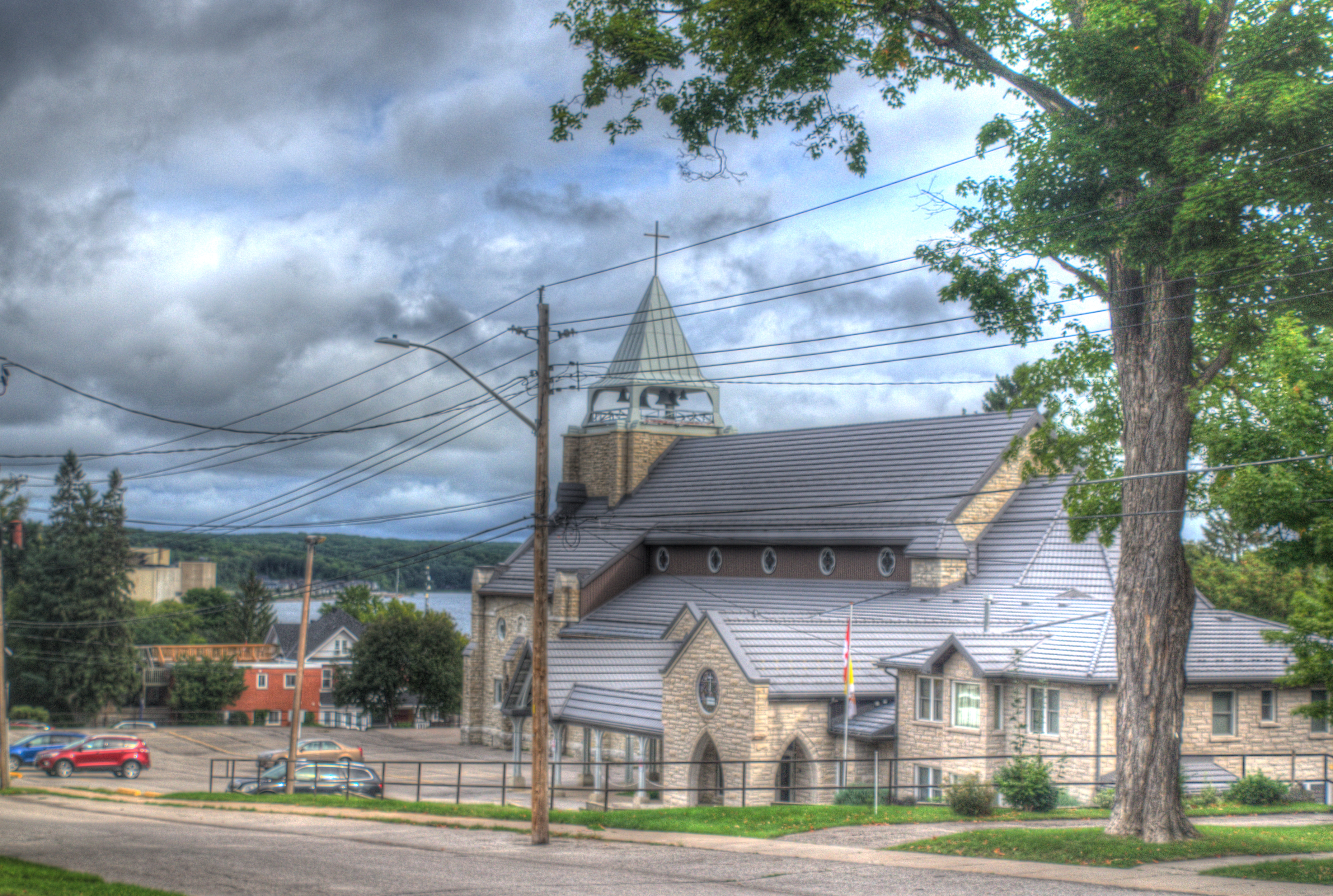 Outside image of St. Margaret's from the view of Third St. with a tree on the right and beautiful clouds.
