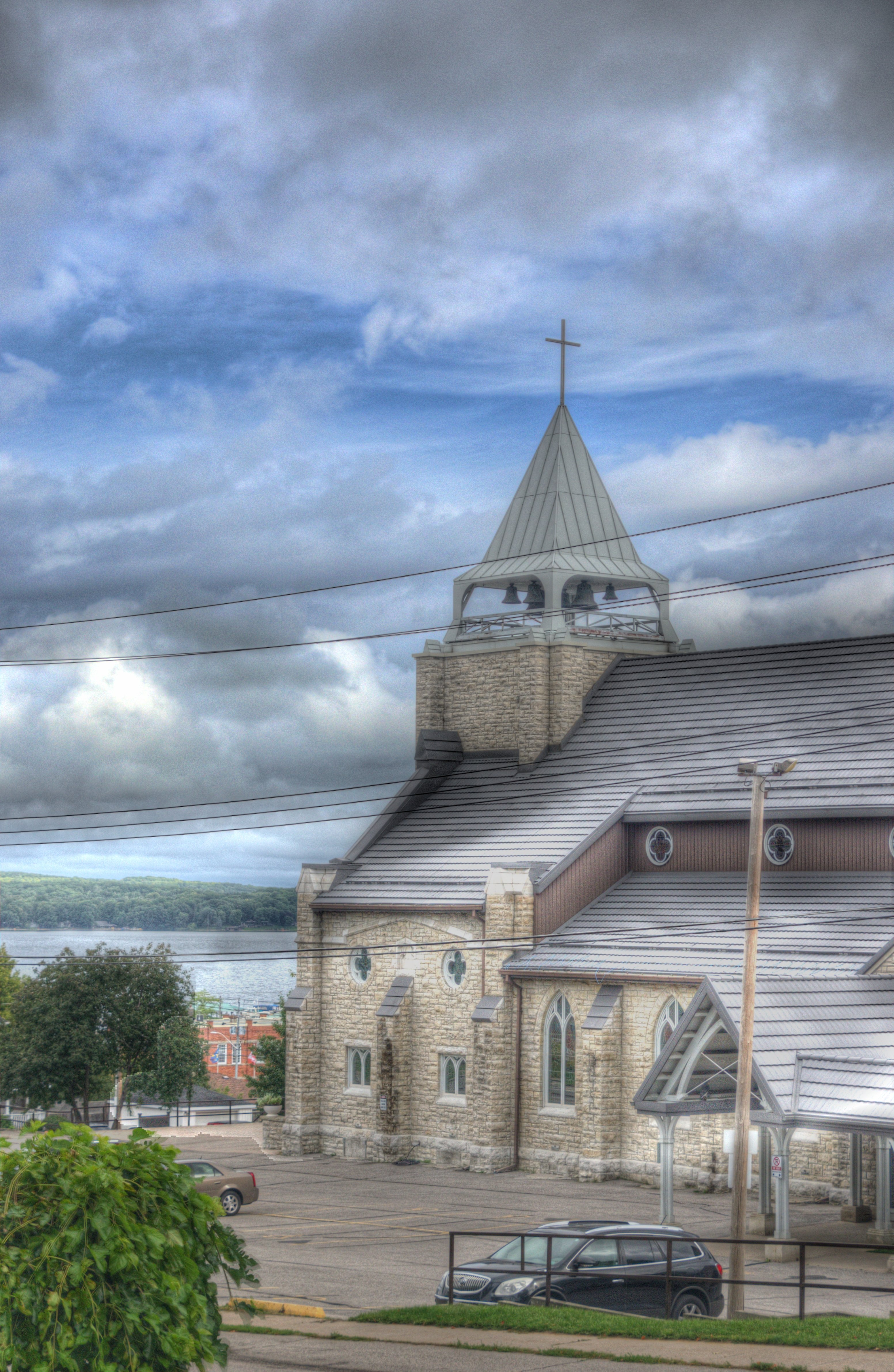 Outside image of St. Margaret's Bell tower from the view of Third St. a view of Georgian Bay and beautiful clouds in the sky.